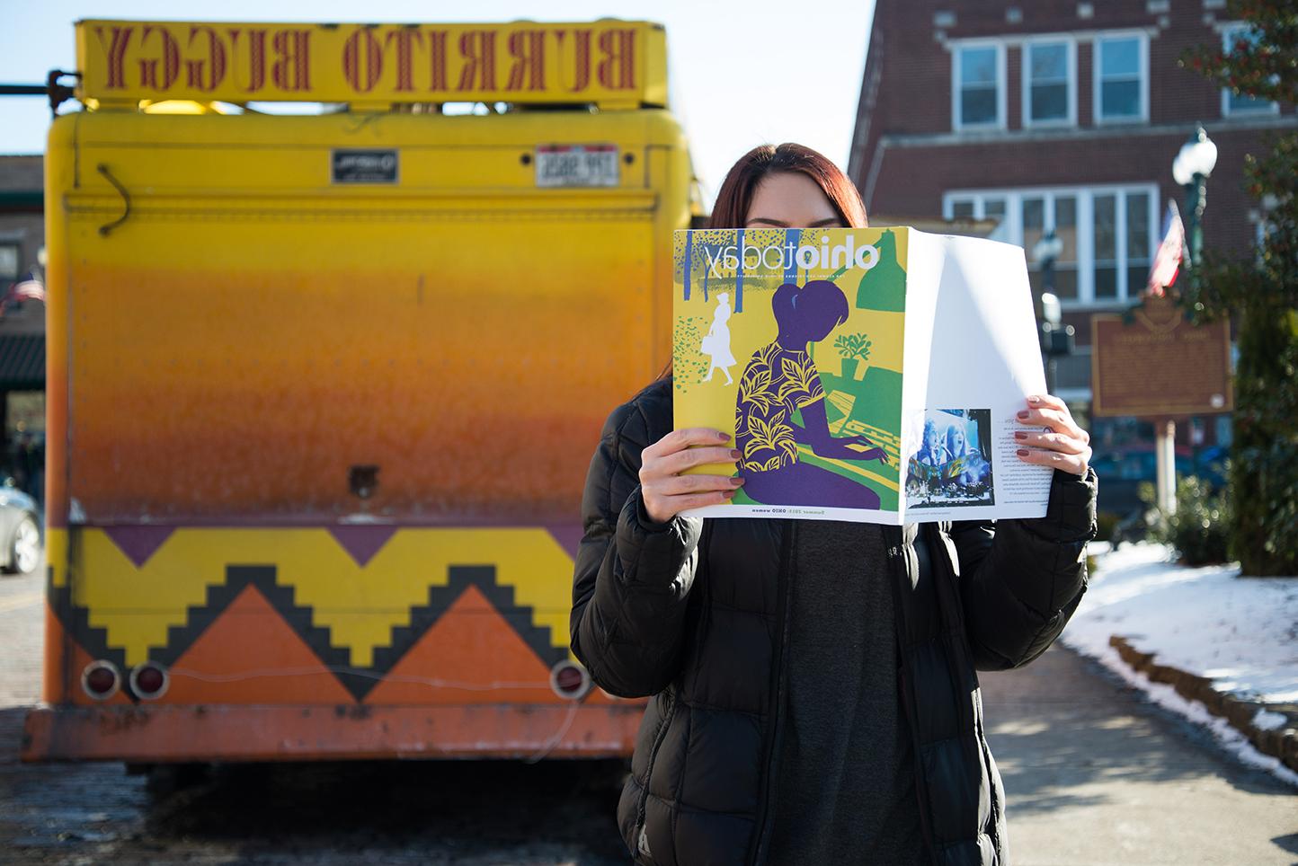 Person reading Ohio Today magazine in front of the Burrito Buggy