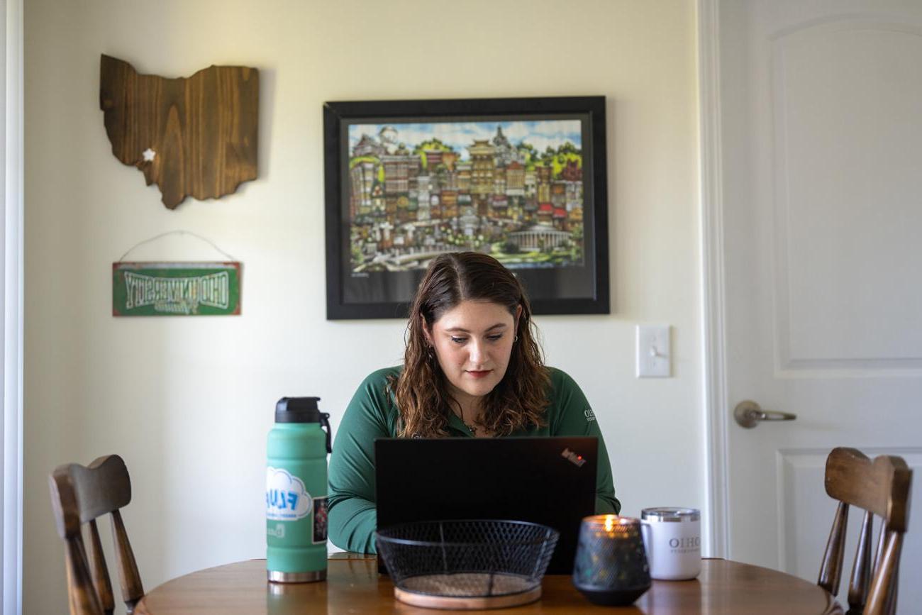 woman sits at laptop in her house