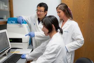 Students and a faculty member perform research in a lab