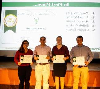 Four students stand next to each other holding first place certificates for the Eco Impact Challenge